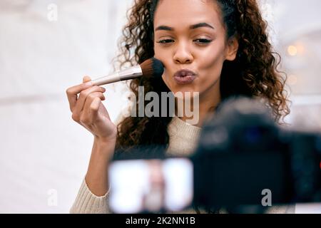 Découvrez les dernières tendances en matière de maquillage. Photo d'une jeune femme qui fait son maquillage tout en enregistrant une vidéo pour son blog. Banque D'Images