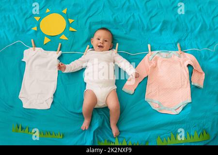 Quelque chose d'incroyable est suspendu sur la ligne. Plan conceptuel d'une petite fille accrochée à la ligne de lavage sur un fond bleu. Banque D'Images