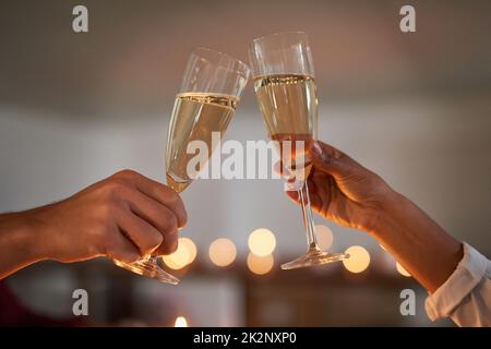 Toasting à des moments extraordinaires ensemble. Gros plan d'un couple non identifiable qui toasque avec des verres de vin. Banque D'Images