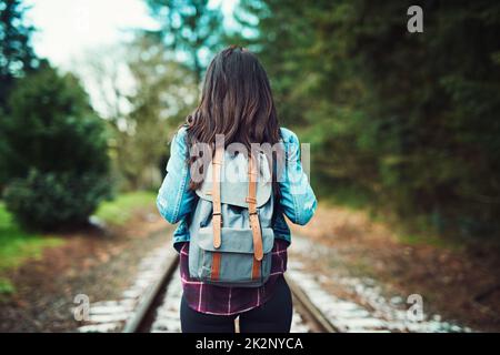 La nature est là où elle aime se demander. Vue arrière d'une femme méconnue qui marche sur les voies de train à l'extérieur. Banque D'Images