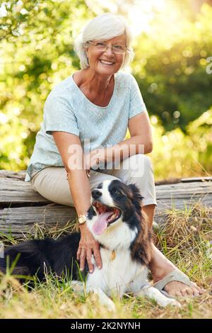 Le compagnon idéal pour la retraite. Portrait d'une femme âgée heureuse qui se détend dans un parc avec son chien. Banque D'Images