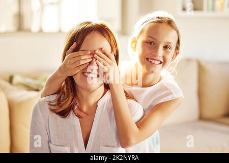 Vous allez adorer ça. Photo d'une adorable petite fille qui se joint à sa mère à la maison et qui couvre ses yeux pour la surprendre. Banque D'Images