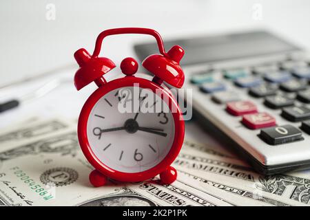 Alarm clock with coins on US dollar banknotes, finance installment loan time. Stock Photo