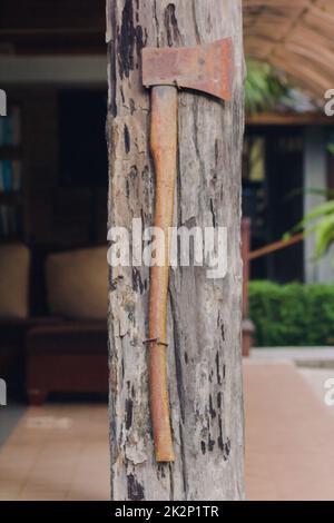 L'ancienne hache de fer est fixée au poteau de maison en bois. Banque D'Images