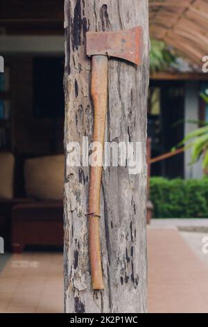 L'ancienne hache de fer est fixée au poteau de maison en bois. Banque D'Images