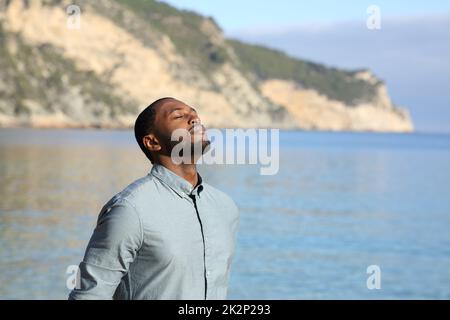 Homme à la peau noire se relaxant et respirant sur la plage Banque D'Images