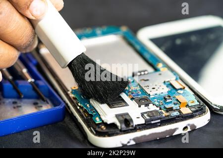 Le technicien utilise une brosse et une boule de soufflerie d'air pour nettoyer la poussière de l'ordinateur de la carte de circuit imprimé. Réparer la technologie de mise à niveau et de maintenance. Banque D'Images