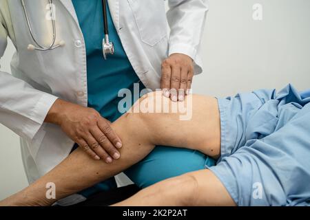 Médecin asiatique physiothérapeute examinant, massant et traitement genou et jambe d'un patient senior dans la clinique orthopédique infirmière hôpital. Banque D'Images