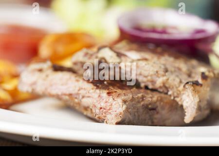 Steak grillé avec oignons rouges sur une plaque Banque D'Images