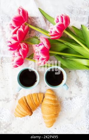 une bonne tasse de café, des croissants et des tulipes roses sur une vieille table blanche, en gros plan Banque D'Images