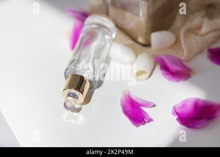 Cosmétiques naturels, un beau pot de liquide pour le visage sur le fond des pétales roses des pivoines. Banque D'Images