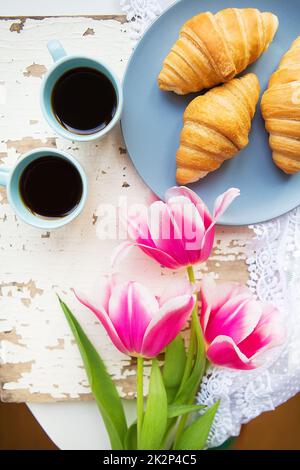 Café, croissants et trois belles tulipes roses sur le vieux tableau blanc Banque D'Images