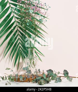 scène pour présenter des produits, des cosmétiques avec un podium rond en bois et un vase en verre avec un bouquet de fleurs. fond beige Banque D'Images