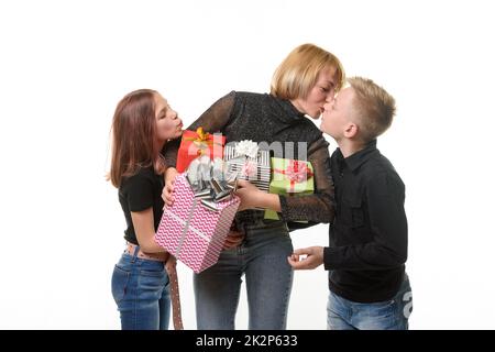 Les enfants ont félicité maman pour son anniversaire et ont donné des cadeaux, maman embrasse son fils comme un signe de gratitude Banque D'Images