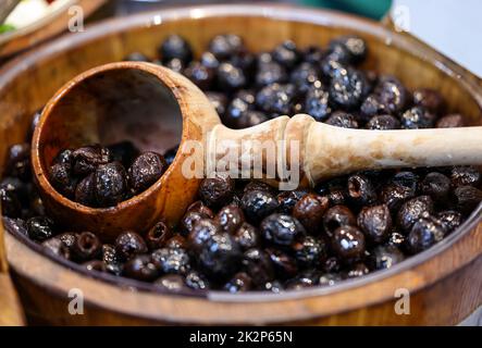Olives noires dans un ancien bol en bois Banque D'Images
