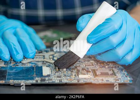 Le technicien utilise une brosse et une boule de soufflerie d'air pour nettoyer la poussière de l'ordinateur de la carte de circuit imprimé. Réparer la technologie de mise à niveau et de maintenance. Banque D'Images