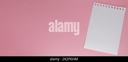 Une feuille de papier blanche déchirée d'un bloc-notes, sur fond rose avec une copie de l'espace Banque D'Images