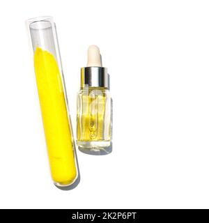 Gros plan sur l'ingrédient chimique sur la table de laboratoire blanche. Liquide cosmétique jaune (huile) dans un flacon compte-gouttes placer à côté de la poudre de chromate de potassium dans le tube à essai. Banque D'Images