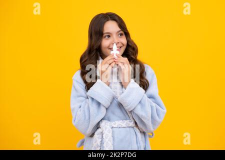 Fille tenir médicament spray nasal de nez courant, pandémie de virus. Jeune fille malade avec vaporisateur nasal sur fond jaune. Banque D'Images