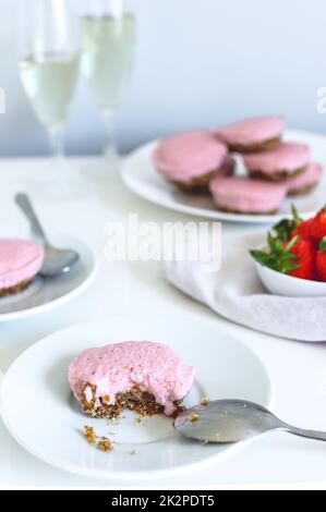 Gros plan vertical d'un cheesecake aux fraises avec des fraises et des verres de champagne à l'arrière Banque D'Images