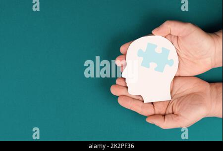 Tenir la tête avec une pièce de puzzle, maladie mentale comme l'autisme, la maladie d'Alzheimer, la conscience d'accident vasculaire cérébral, brainstorming pour des idées, problèmes de mémoire Banque D'Images