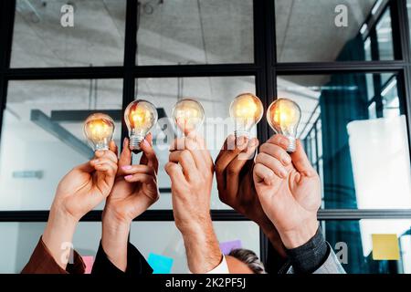 Travail d'équipe et remue-méninges avec des hommes d'affaires qui partagent une idée avec une lampe Banque D'Images