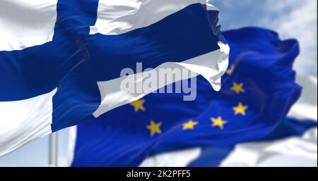 Détail du drapeau national de la Finlande qui agite dans le vent avec un drapeau flou de l'Union européenne en arrière-plan par temps clair Banque D'Images