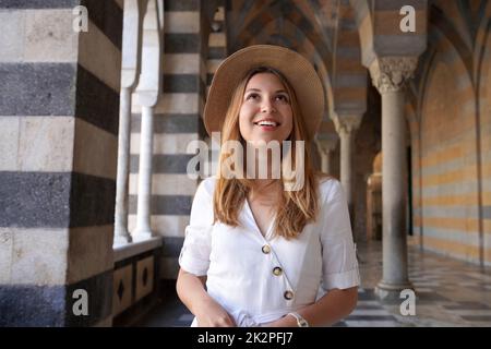 Belle jeune femme regarde quand elle marche dans la colonnade à l'extérieur de la cathédrale d'Amalfi, en Italie Banque D'Images