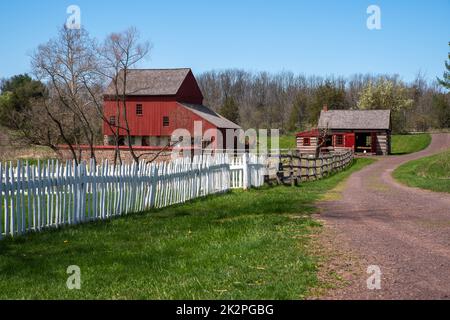 Route de terre avec une clôture de piquetage et une grange rouge coloniale américaine et une cabane en rondins Banque D'Images