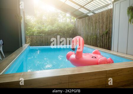 Anneau gonflable rose plastique flamant dans l'eau bleue de la piscine Banque D'Images