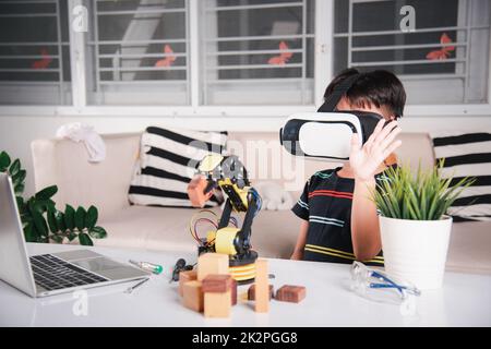 Enfant asiatique utilisant des lunettes VR sur le bras robotique dans l'atelier Banque D'Images