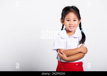 Asiatique tout-petit sourire heureux porter étudiant thaïlandais uniforme rouge jupe stand avec les bras pliés Banque D'Images