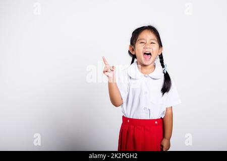 Asiatique tout-petit sourire Happy Wear étudiant thaïlandais uniforme rouge jupe continue de pointer le doigt sur l'espace de copie Banque D'Images