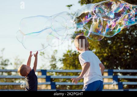 garçons jouant avec des bulles de savon Banque D'Images