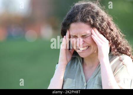 Une femme se plaint d'une migraine dans un parc Banque D'Images