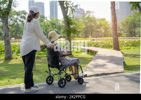 Aide-soignant et soins asiatique senior ou âgée vieille femme patiente assise en fauteuil roulant dans le parc, concept médical sain et fort. Banque D'Images