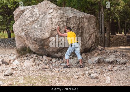 L'homme se tient devant un grand rocher. Tâche de faire face. Banque D'Images