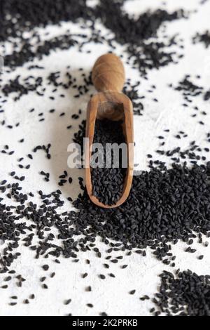 Une cuillère en bois de graines de cumin noir d'épices indiennes (nigella sativa ou kalonji) est en gros plan Banque D'Images