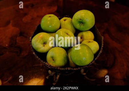 Pommes vertes bio dans un bol vintage avec fond texturé brun Banque D'Images