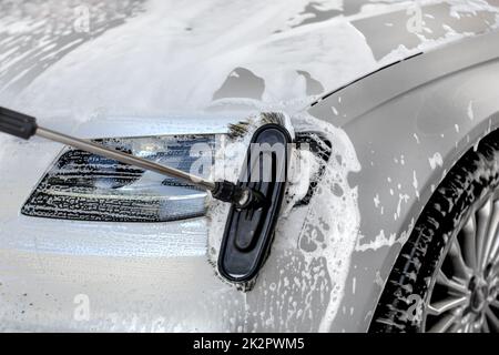 Détail sur l'argent phare de voiture lavés à carwash manuel, brosses de nettoyage du verre. Banque D'Images