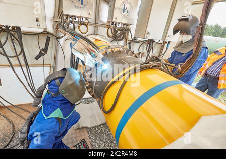 23 September 2022, Schleswig-Holstein, Brunsbüttel: Two welders in a welding tent weld pipes together on the pipeline for the planned floating liquefied natural gas terminal. Photo: Georg Wendt/dpa Stock Photo