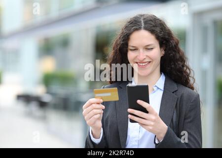 Bonne femme d'affaires achetant en ligne avec carte de crédit et téléphone Banque D'Images