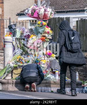 Pupils view floral tributes at the scene in Woodhouse Hill, Huddersfield, where 15-year-old schoolboy Khayri McLean was fatally stabbed outside his school gates. Picture date: Friday September 23, 2022. Stock Photo