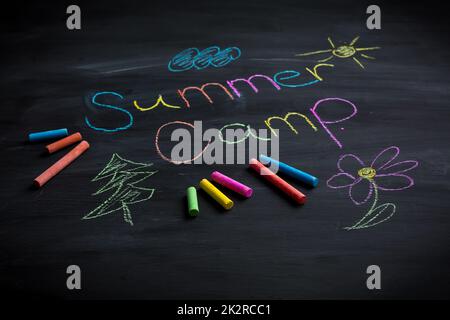 Texte camp d'été écrit sur tableau noir, avec des bâtons de craie de différentes couleurs Banque D'Images