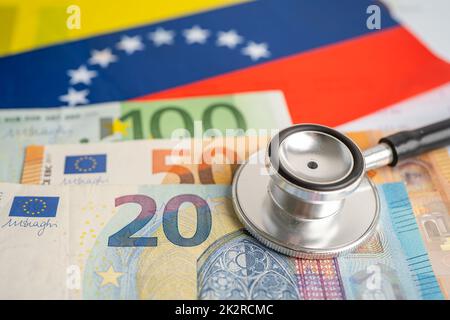 Stéthoscope noir avec billets en euros sur fond de drapeau vénézuélien, concept d'affaires et de finances. Banque D'Images