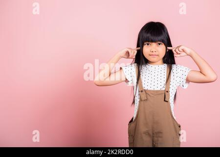 Petit enfant asiatique de 10 ans Fermez ses oreilles avec les doigts et les yeux Banque D'Images