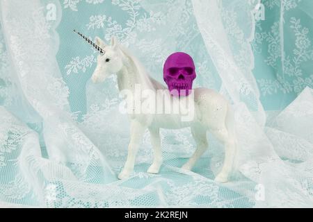 une licorne blanche brillante portant un crâne en plastique sur son dos Banque D'Images