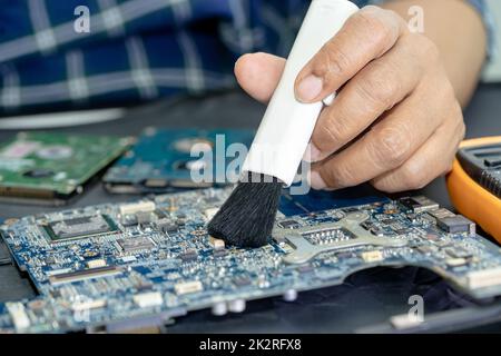 Le technicien utilise une brosse et une boule de soufflerie d'air pour nettoyer la poussière de l'ordinateur de la carte de circuit imprimé. Réparer la technologie de mise à niveau et de maintenance. Banque D'Images