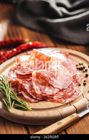 Tranché de saucisse italienne de salami avec du poivre sur la planche à découper. Banque D'Images