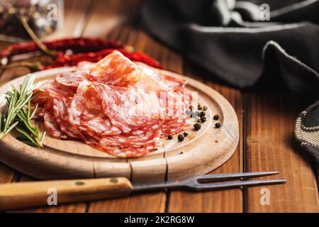 Tranché de saucisse italienne de salami avec du poivre sur la planche à découper. Banque D'Images